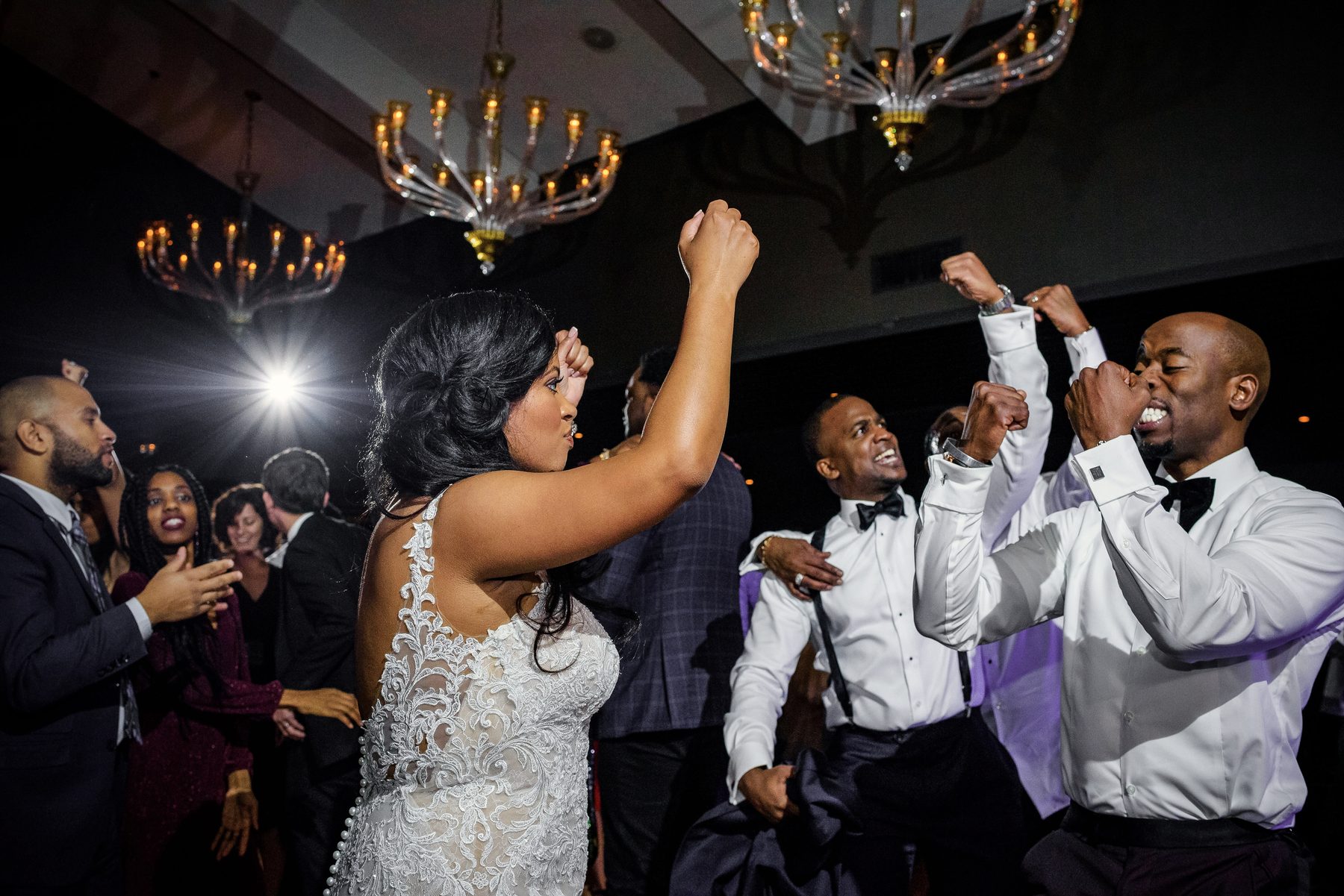 Bride dancing with fists raised alongside groomsmen at the reception