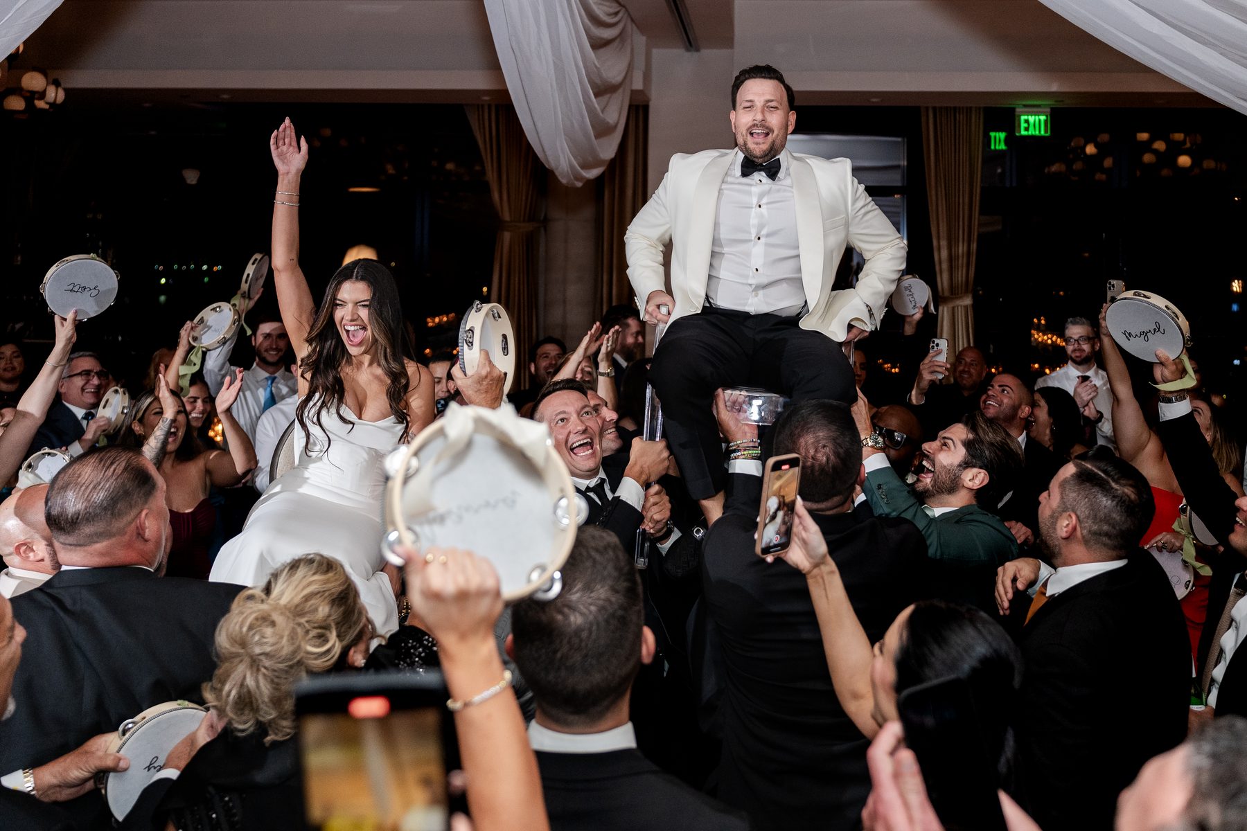 Bride and groom lifted on shoulders as guests celebrate with tambourines