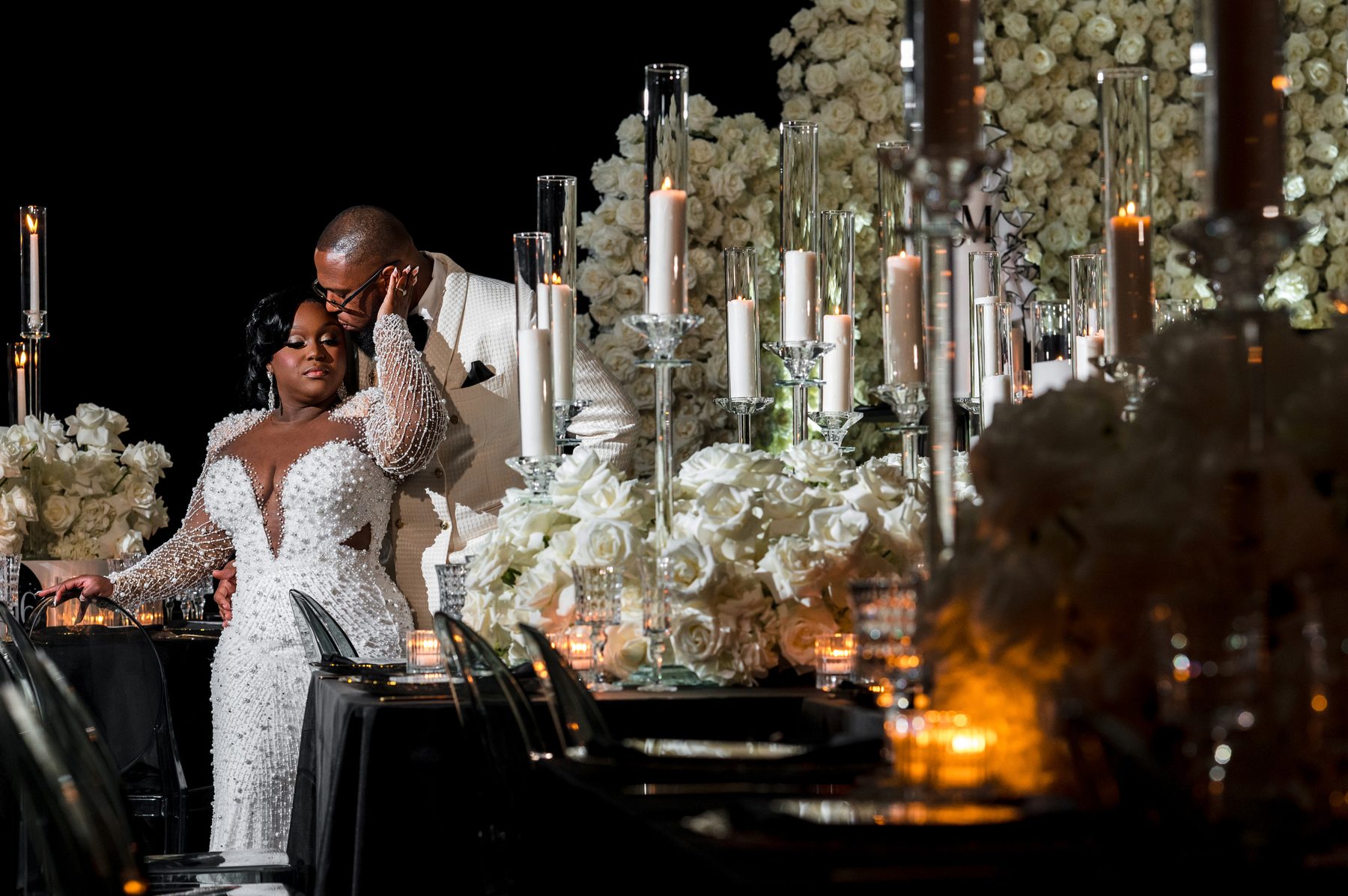 Bride and groom sharing a quiet moment beside a candlelit reception table