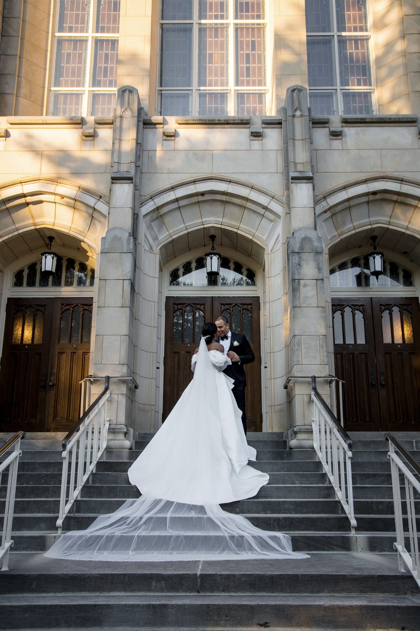 Bride and groom embracing on the steps of a grand stone church
