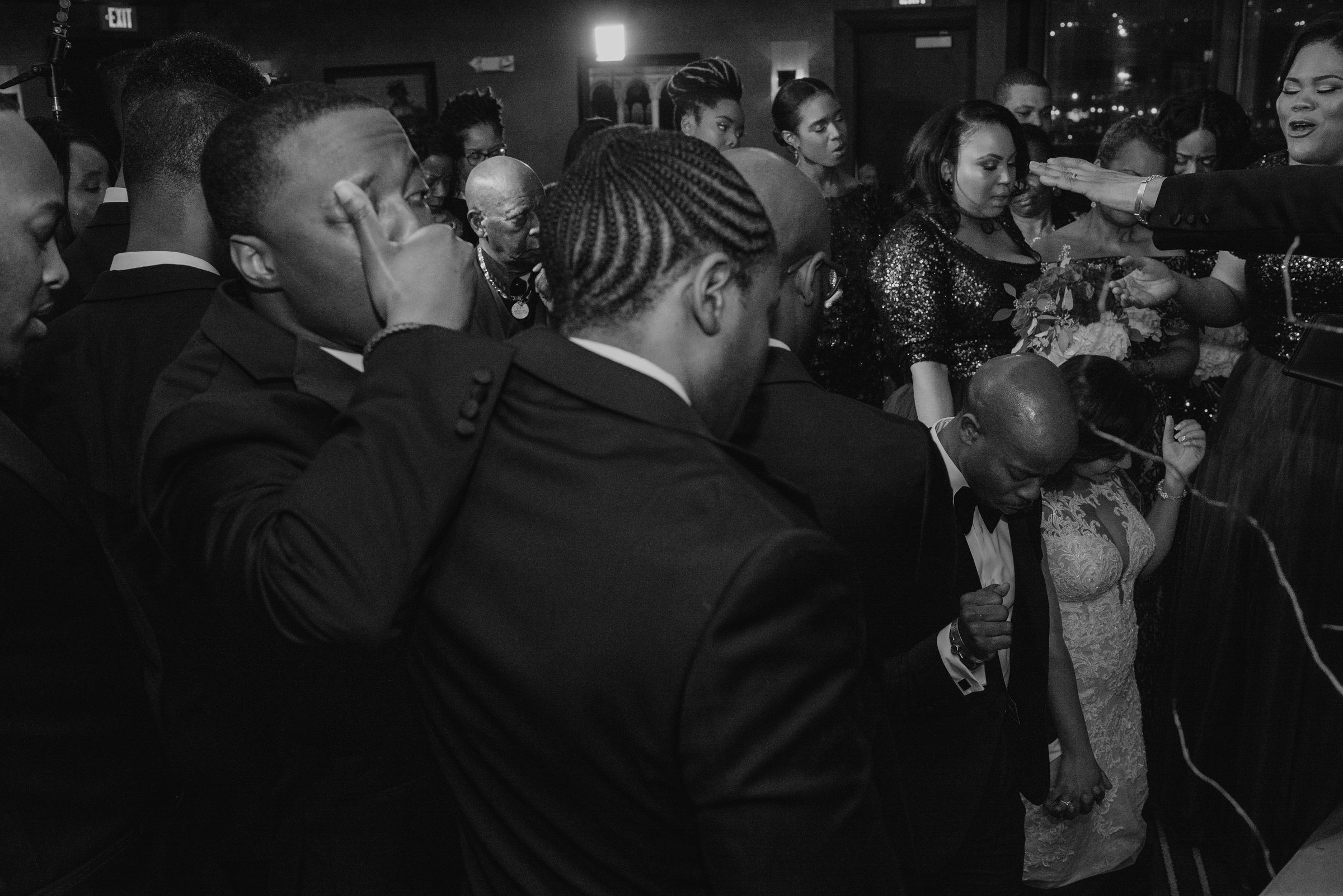 Black and white photo of guests dancing together at a crowded reception
