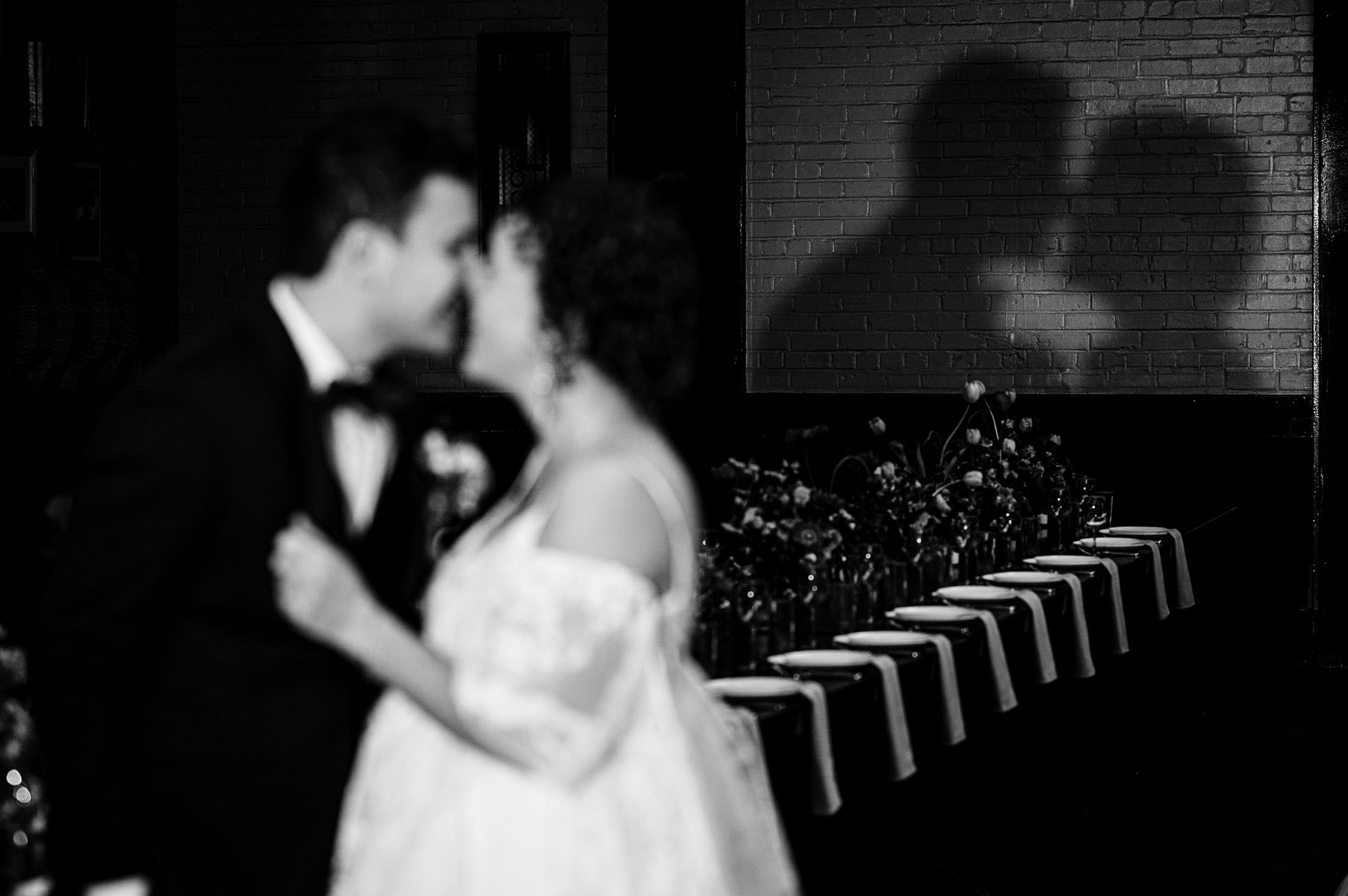 Black and white photo of a couple dancing beside a long candlelit dinner table