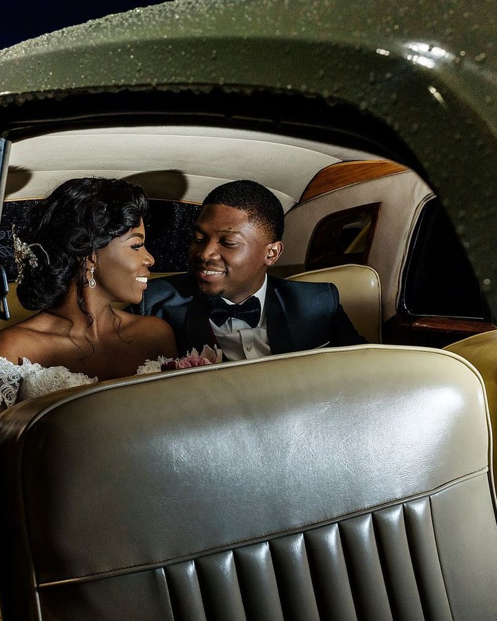 Esther and Tunmise smiling at each other in the back seat of a vintage car at night