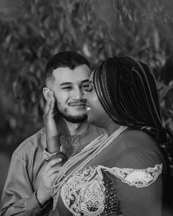 Black and white photo of Sylvia resting her hand on Ricardo’s face as they smile, foreheads close