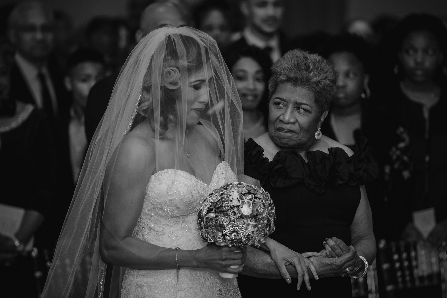 Black and white photo of a mother adjusting her daughter's veil and holding her hand before the ceremony