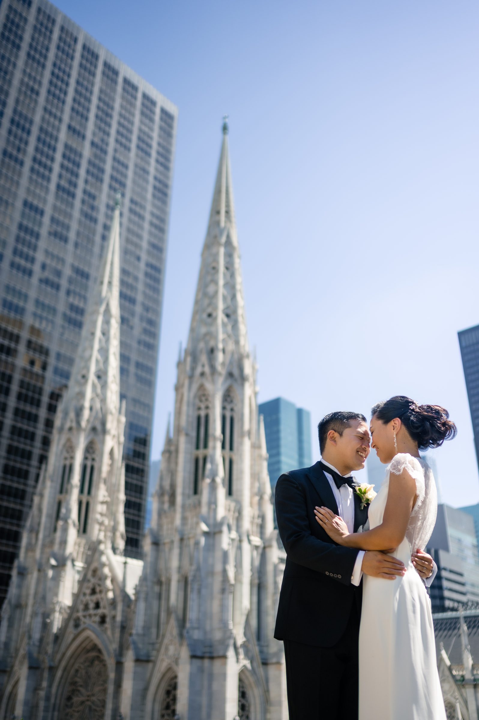 Bride and groom embracing on a rooftop with cathedral spires rising behind them