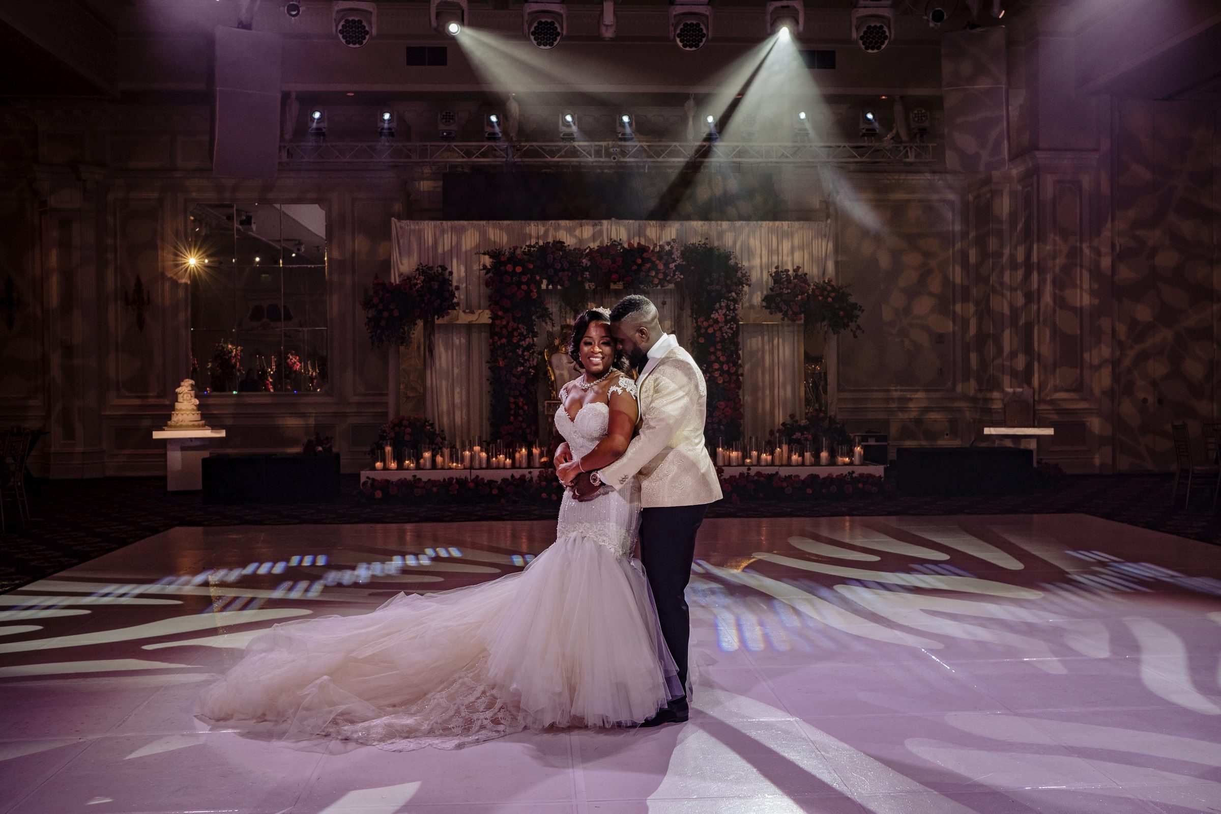 Bride and groom sharing a private dance beneath dramatic spotlights on an empty dance floor